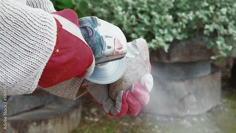 Artist cuts stone with a grinder. Hand held camera of an artist grinding the stone holding in his hand. Artist cuts stone with a grinder. Hand held camera of an artist grinding the stone holding in his hand.