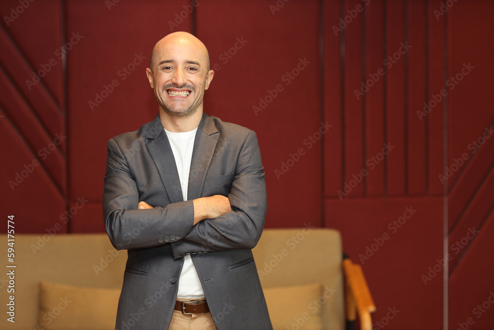 Fototapeta premium Portrait of attractive and handsome caucasian businessman in suit standing and crossing arms while looking away with confident happy face in modern office. Success business and technology concept