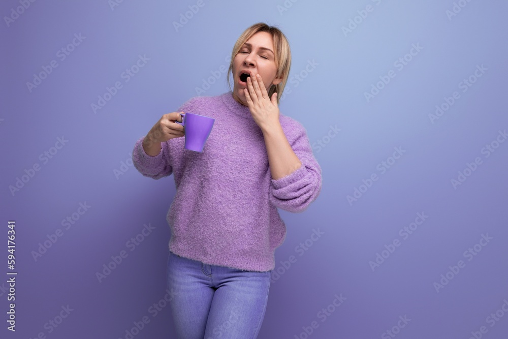 lovely blond young millennial woman in a casual look invigorates with a cup of coffee on a bright background with copy space lovely blond young millennial woman in a casual look invigorates with a cup of coffee on a bright background with copy space