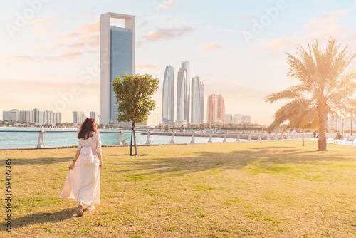 A woman takes a leisurely stroll through the park in Abu Dhabi, enjoying the shade of the palm trees and the cool sea breeze blowing in from the Persian Gulf.