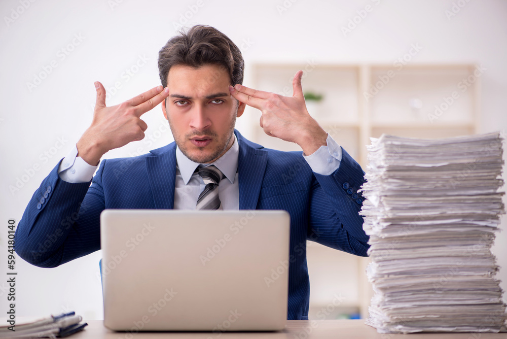 Young male employee and too much work in the office Young male employee and too much work in the office