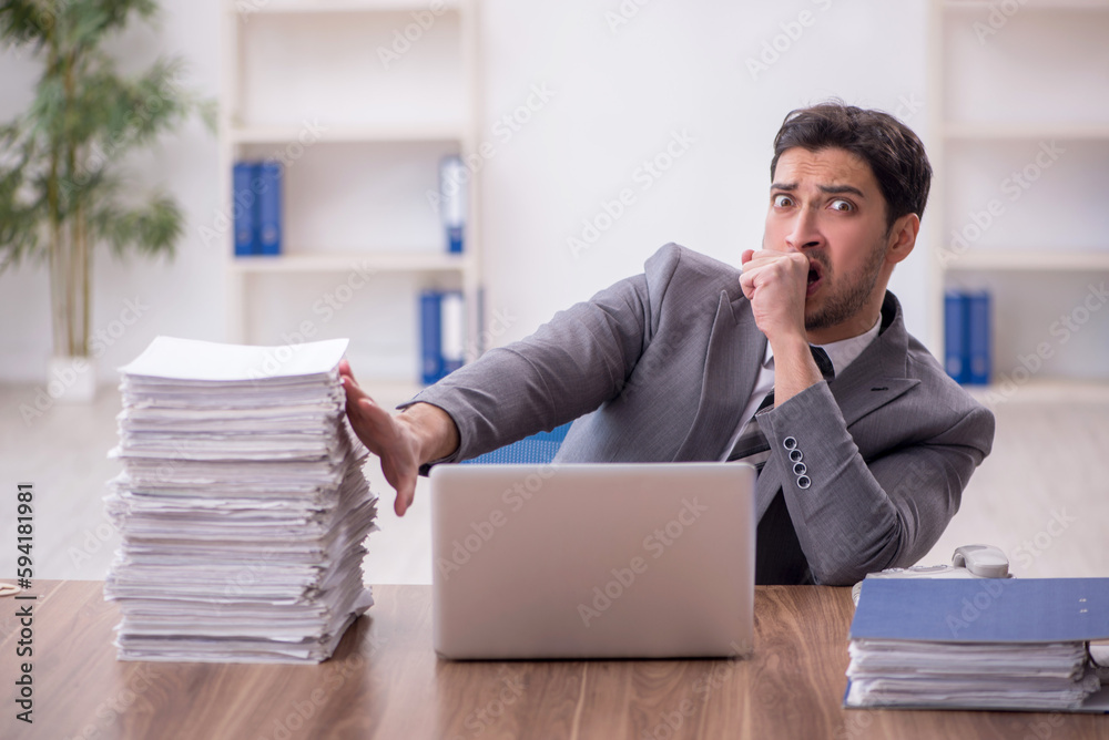 Young male employee and too much work in the office Young male employee and too much work in the office