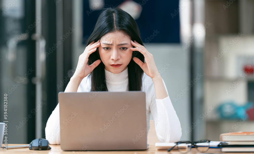 Woman working on laptop having a headache Woman working on laptop having a headache