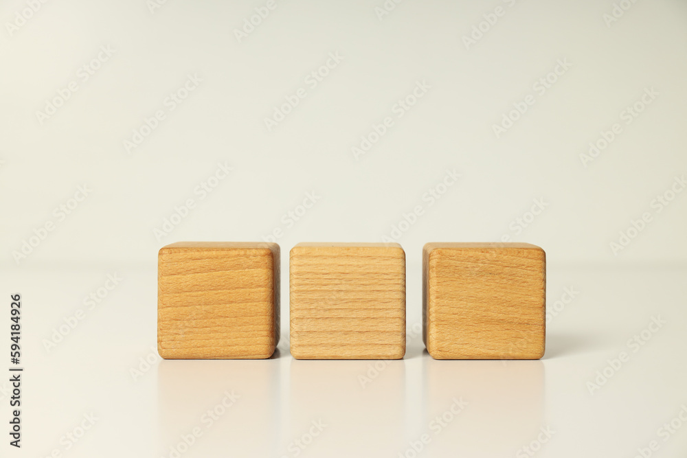 Three wooden cubes on white table, close up