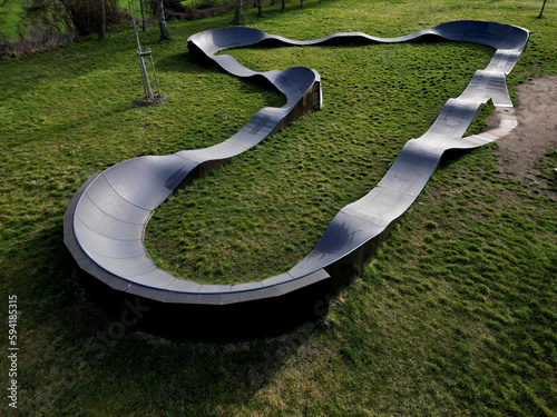 bike path in the car park Pumping (moving up and down) is used instead of pedaling and bouncing to move bicycles, scooters, skateboards and inline skates along the modular pumptrack track, oval, drone photo