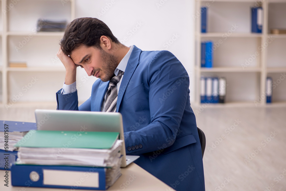 Young male employee and too much work in the office Young male employee and too much work in the office