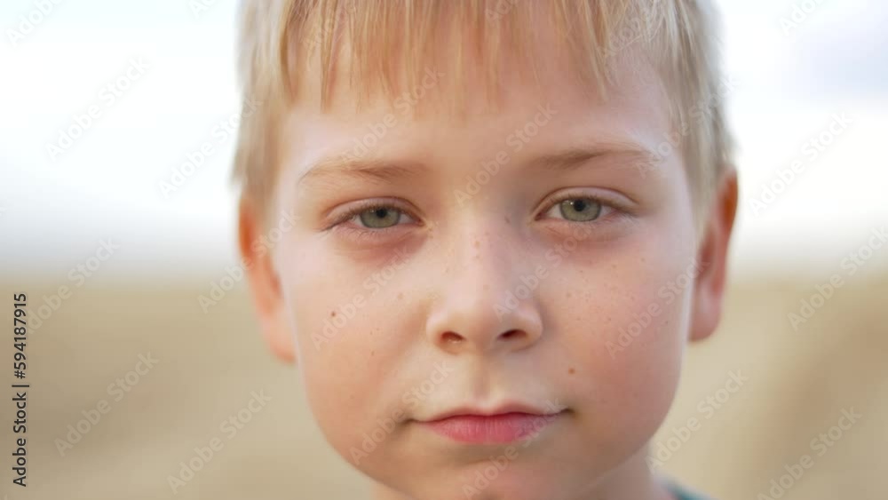 Boy's face close-up looks into camera lens. Blond-haired boy with freckles close-up. face of blue-eyed boy with freckles close-up. Boy's face close-up looks into camera lens. Blond-haired boy with freckles close-up. face of blue-eyed boy with freckles close-up.