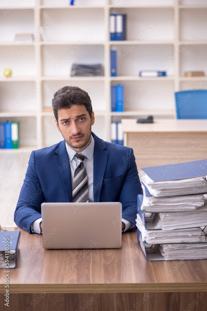 Young male employee and too much work in the office Young male employee and too much work in the office