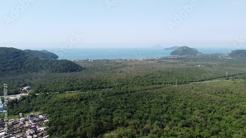 Lush vegetation, Cambury beach in background, Brazil. Aerial flying backwards photo