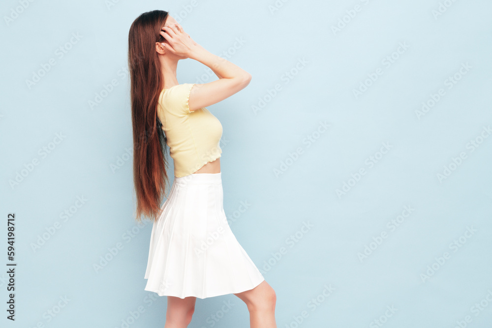 Fototapeta premium Image portrait of optimistic woman in yellow t-shirt and white skirt. Carefree stylish model with long hair. Smiling female posing in studio. Isolated. Looks delightful and cute. Slim