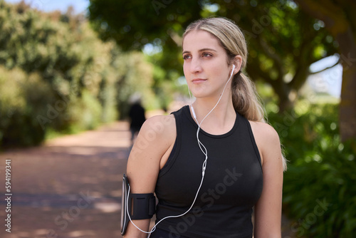 Headphones, runner or woman thinking in park training, exercise or workout for a healthy body. Wellness, fitness break or sports girl athlete exercising or streaming audio or radio song in nature