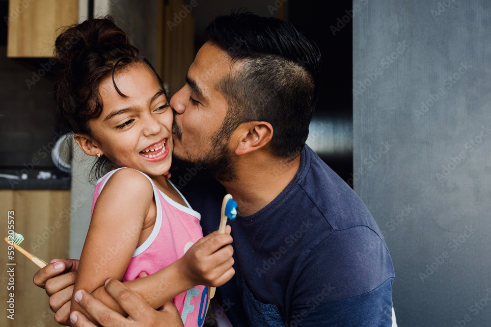 Obraz premium latin young father teaching to his daughter how to brush teeth at home in Mexico Latin America 