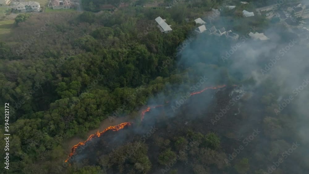 Drone shot of smoke from a forest fire on an island with the flames visible. Drone shot of smoke from a forest fire on an island with the flames visible.