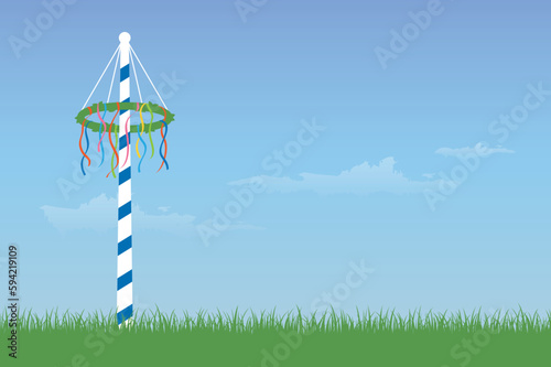 maypole with colorful ribbons on green meadow