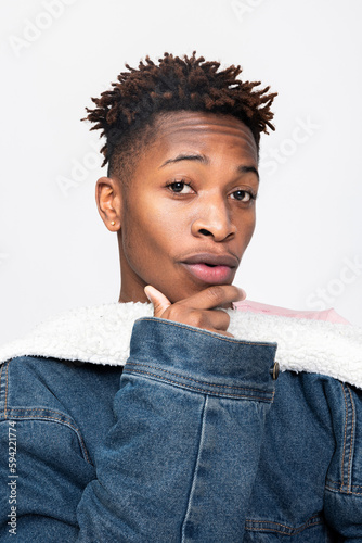 Dark skinned man with beautiful careskin looking at camera posing over white background in fashionable denim clothes. photo