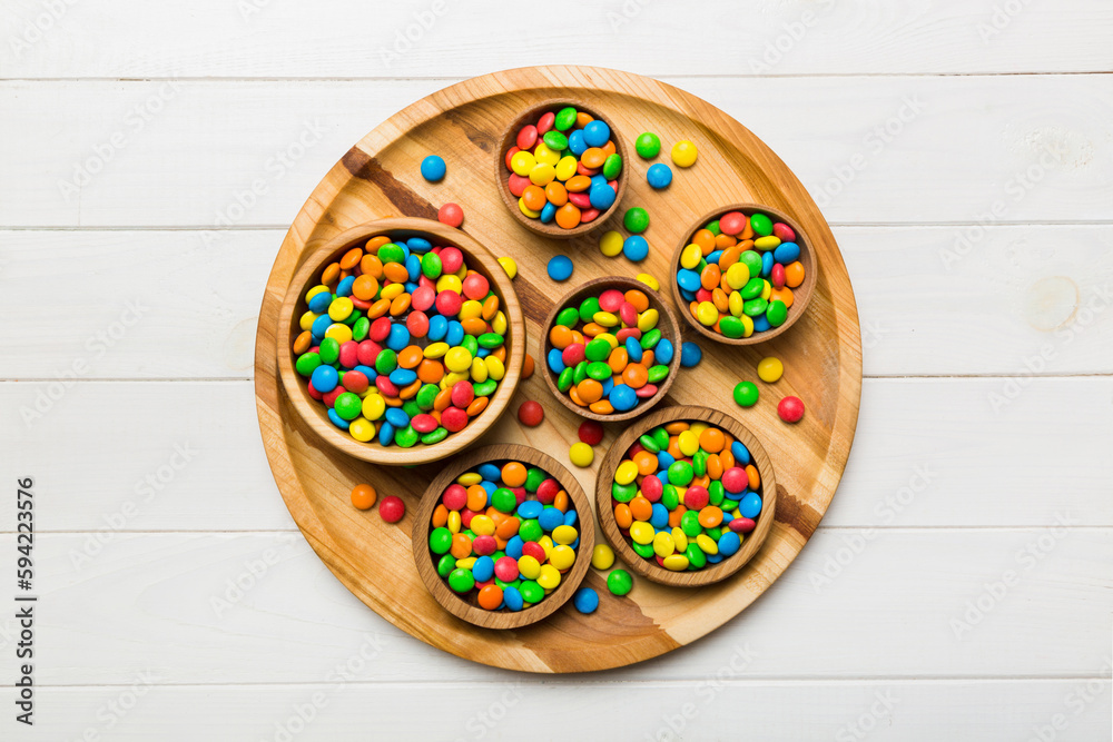 Fototapeta premium different colored round candy in bowl and jars. Top view of large variety sweets and candies with copy space