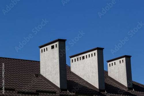 Fototapeta Naklejka Na Ścianę i Meble -  Red house roof with red brick chimney. Ceramic chimney, metal roof tiles, gutters