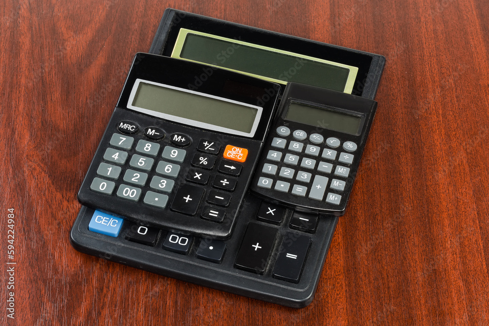 Different used modern electronic calculators on a wooden table Different used modern electronic calculators on a wooden table
