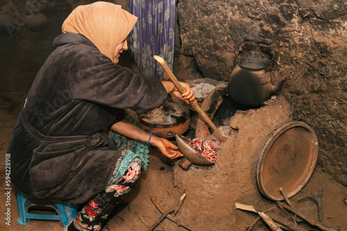 Berber woman in old traditional kitchen preparing wood oven for cooking