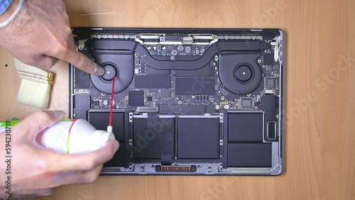 Blowing dusty fan inside a notebook with canned air. Laptop teardown and cleaning.