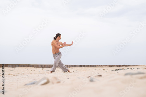 Caucasian man practices martial arts outdoors. balance and meditation.