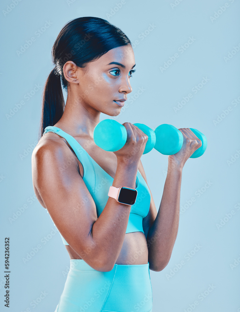 Fitness, workout and woman with weights in a studio for a arm or strength training with motivation. Sports, health and Indian female athlete or model doing exercise while isolated by blue background. Fitness, workout and woman with weights in a studio for a arm or strength training with motivation. Sports, health and Indian female athlete or model doing exercise while isolated by blue background.
