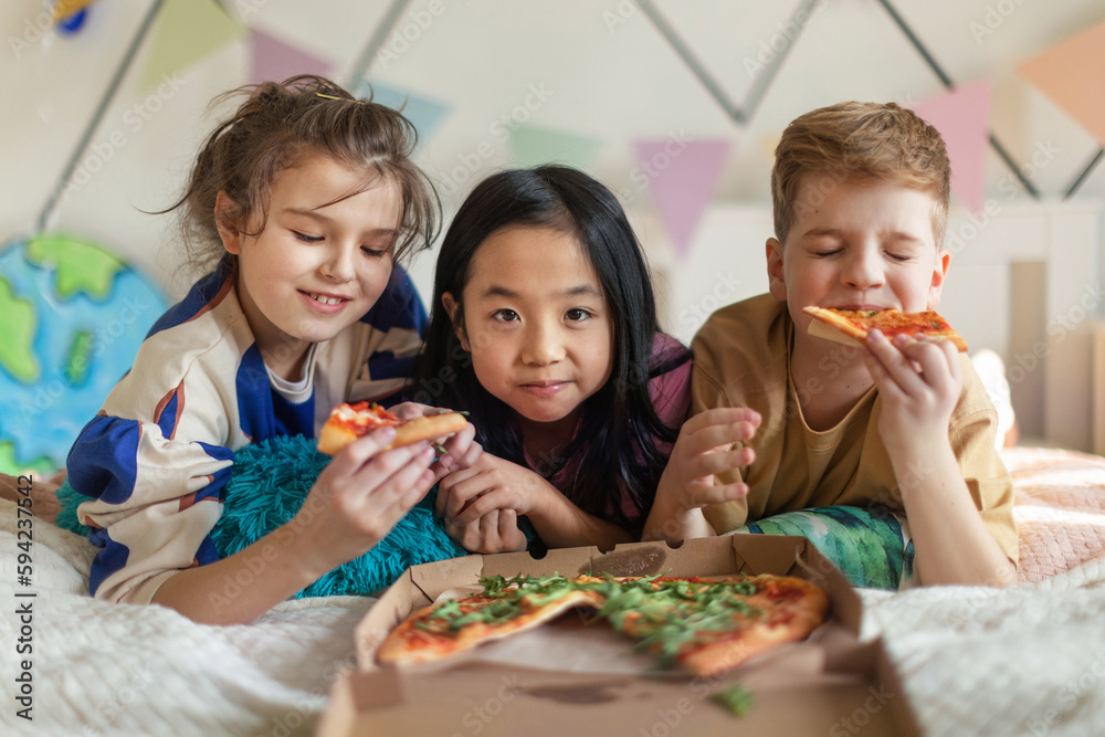 Happy friends lying on a bed and eating pizza. Happy friends lying on a bed and eating pizza.