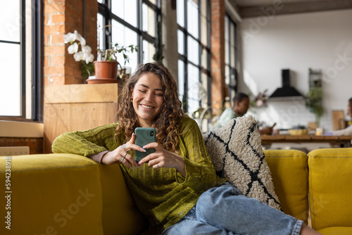 Female Student on Sofa using a Smartphone in loft apartment