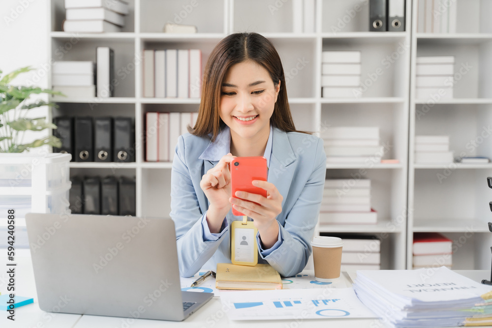 Asian businesswoman in formal suit in office happy and cheerful during using smartphone and working Asian businesswoman in formal suit in office happy and cheerful during using smartphone and working