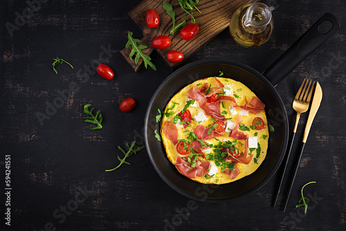 Omelet with tomatoes, jamon and feta cheese in pan. Top view