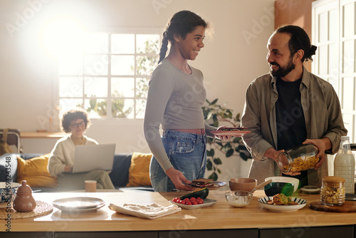 Adopted African American daughter helping to her dad in the kitchen, they talking and preparing breakfast together