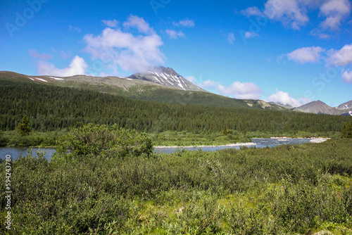 Manaraga peak in Nether-Polar Ural mountains, Russia at sunny summer day. Forest and river on foreground, helicopter flying photo