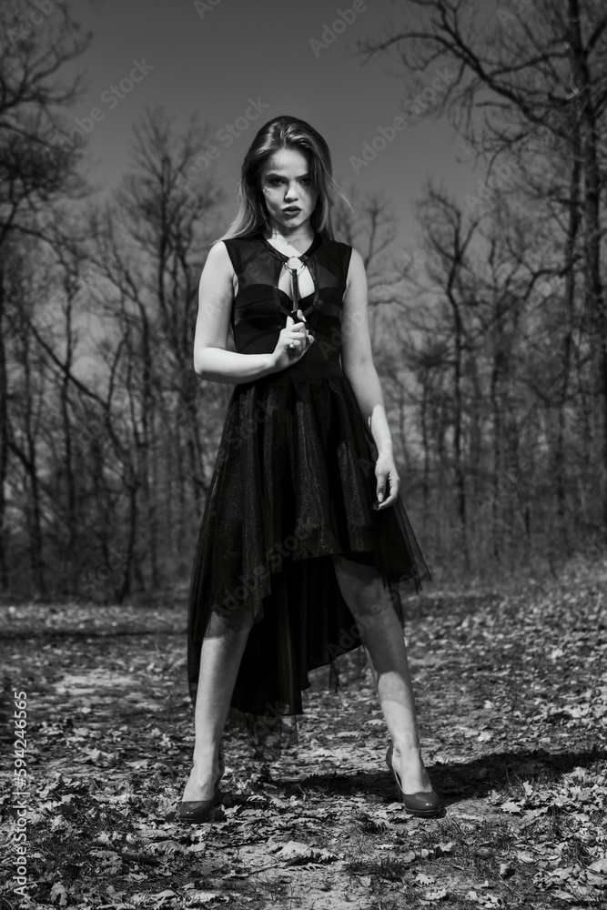 Grayscale vertical shot of a Caucasian female posing in the forest