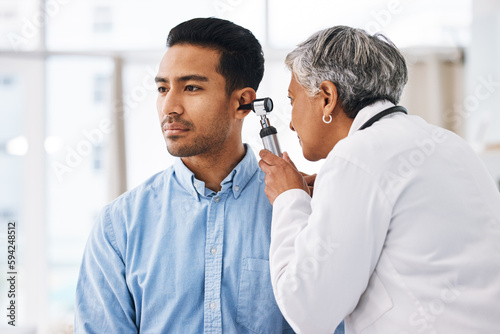 Doctor check patient ear, consultation and healthcare, people at hospital with otolaryngology specialist. Man and senior physician woman with otoscope test for hearing problem and health insurance photo