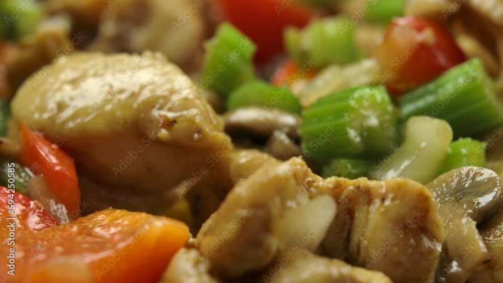 The spatula stirs the fried pieces of chicken meat, vegetables and mushrooms The spatula stirs the fried pieces of chicken meat, vegetables and mushrooms