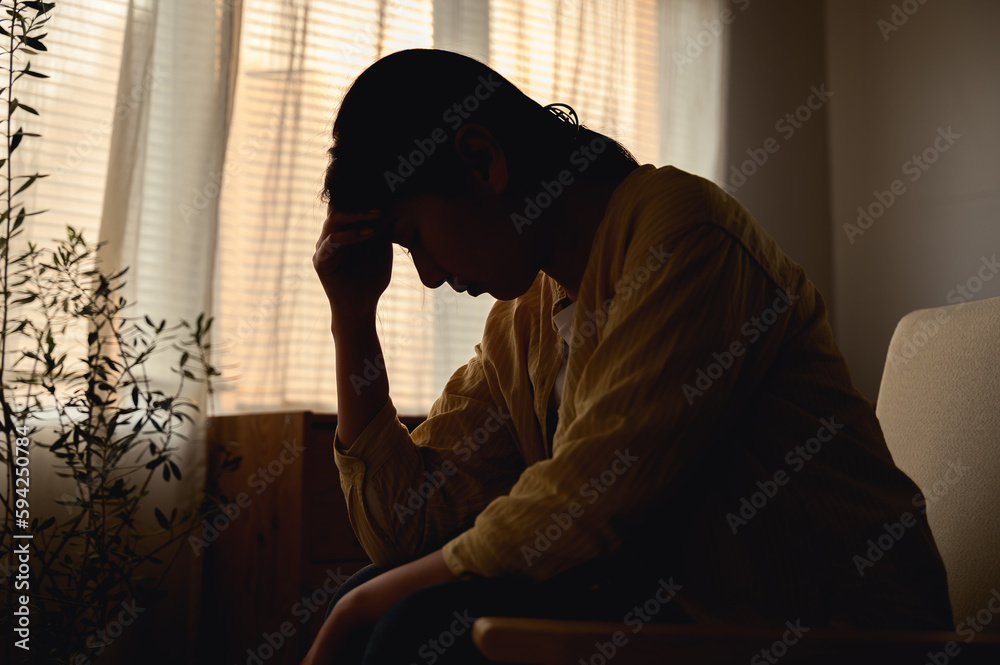 Silhouette photo of young Asian woman feeling upset, sad, unhappy or disappoint crying lonely in her room. Young people mental health care problem lifestyle concept. Silhouette photo of young Asian woman feeling upset, sad, unhappy or disappoint crying lonely in her room. Young people mental health care problem lifestyle concept.