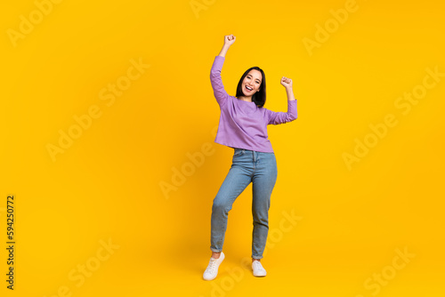 Full size photo of satisfied girl with bob hairdo dressed violet shirt denim pants dancing having fun isolated on yellow color background © deagreez