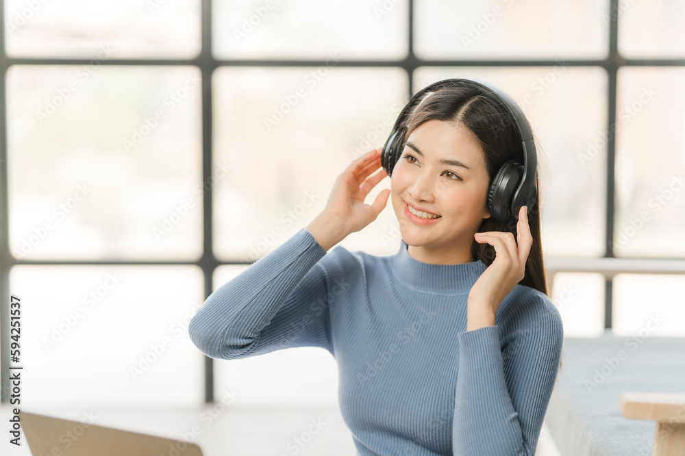 Beautiful smiling young woman in headphones chatting via laptop computer video call at home Beautiful smiling young woman in headphones chatting via laptop computer video call at home