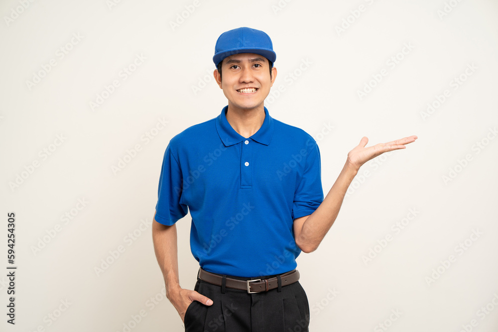 Happy delivery asian man in blue uniform standing on isolated white background. Smiling male delivery service worker pointing the finger to blank space. Courier and shipping service. Happy delivery asian man in blue uniform standing on isolated white background. Smiling male delivery service worker pointing the finger to blank space. Courier and shipping service.
