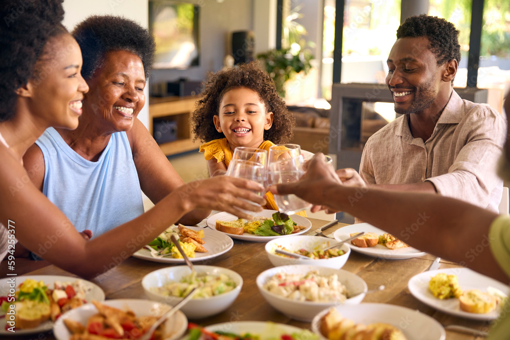 Multi-Generation Family Around Table Doing Cheers With Water Before Serving Food For Meal At Home 