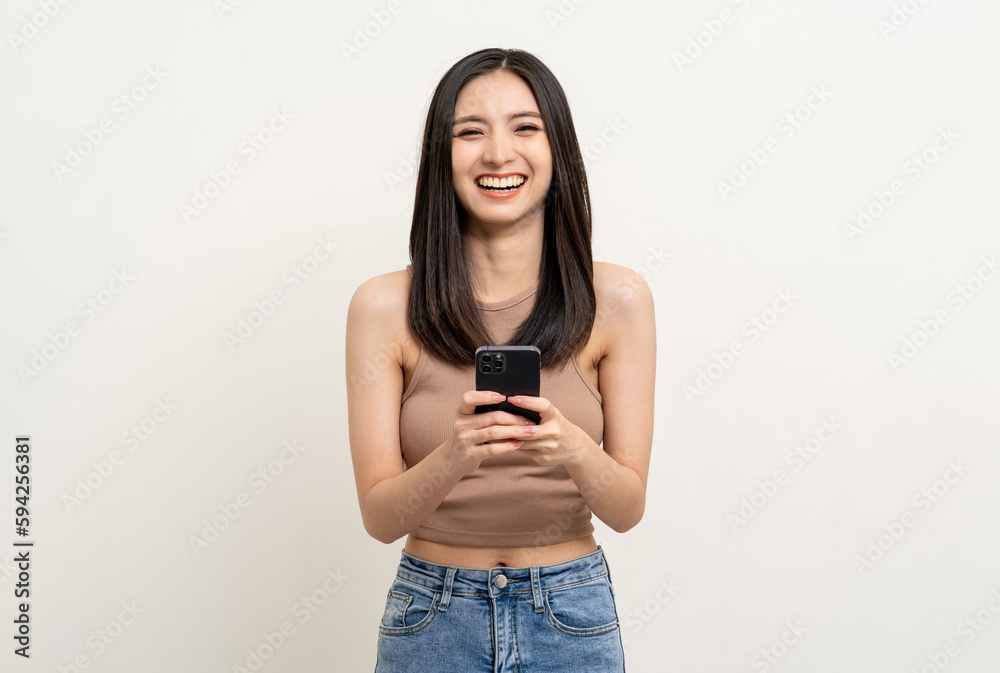 Pretty young asian woman using smartphone standing on isolated white background. Excited Beautiful young asian shopping online payment with mobile phone. Playing game on smartphone
