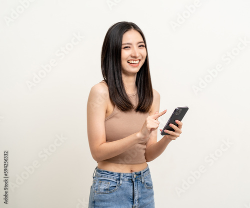 Pretty young asian woman using smartphone standing on isolated white background. Excited Beautiful young asian shopping online payment with mobile phone. Playing game on smartphone