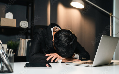 The business man worked so hard that he fell asleep at his desk. Working overtime because it's almost time for the deadline. He was tired from job and took a nap.
