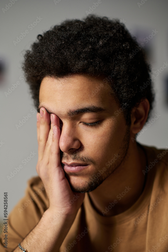 Vertical image of young sad man with eyes closed worried about his problems Vertical image of young sad man with eyes closed worried about his problems