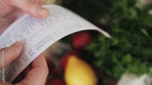 The buyer holds a purchase receipt in hands, checks purchases and prices.