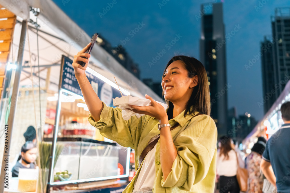 Asian woman enjoy eating fries street food at night market. Traveler Asian blogger women Happy tourists Beautiful female with Traditional thailand bangkok food. - obrazy, fototapety, plakaty 