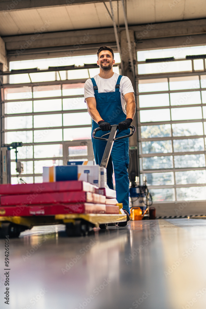 Caucasian professional male mechanic pulls, trolley with repair parts. Service, maintenance, people concept. Side view. Selective focus. Web Banner