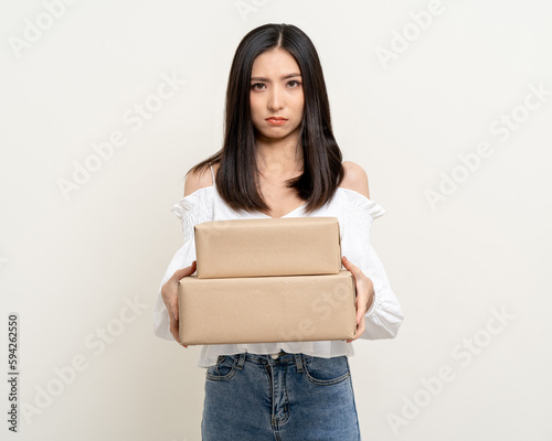 Upset confused bad emotional asian woman with parcel cardboard. Unhappy stressed female receive wrong product from delivery man. © Chanakon