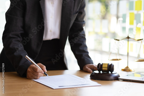 Female lawyer working in the office reading documents and signing legal agreement contracts.