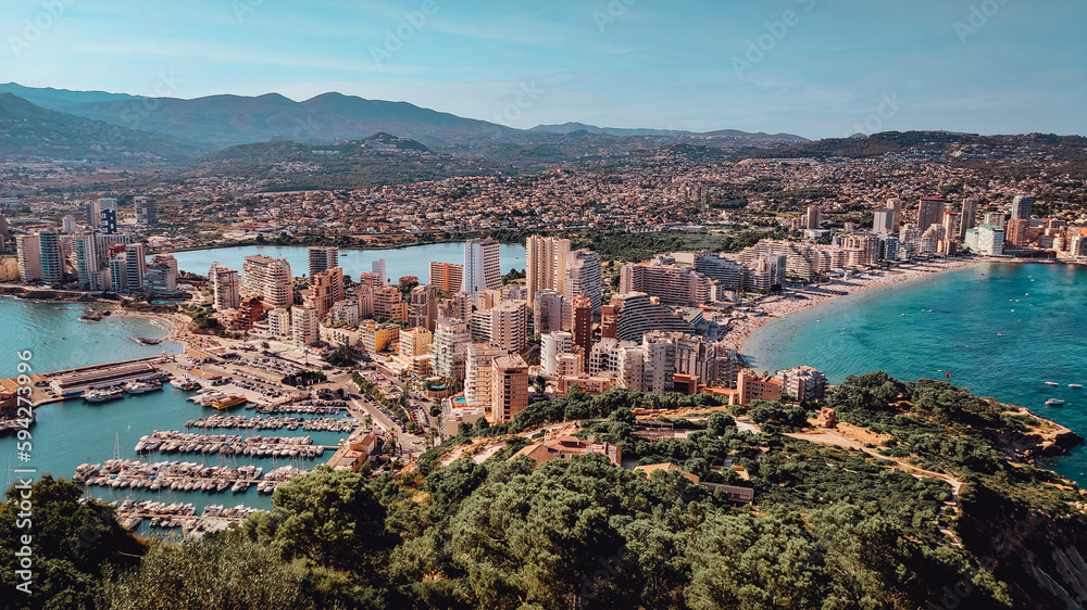 Panorama of the city of Calpe, province of Alicante, seen from the Penon de Ifach. Summer holidays in Costa Blanca. Beaches and port with boats and yachts. Travel, hiking, sea vacation concept